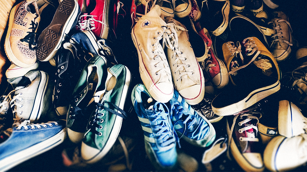 A large collection of converse all star shoed piled high in a closet